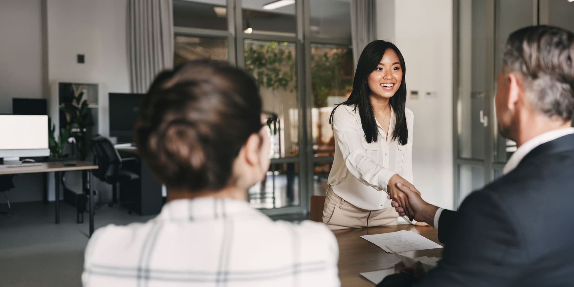 A candidate shaking hands across the table at the end of an interview
